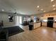 Open concept showcasing a large kitchen area and living room with stainless steel appliances, dark furniture, and tile floors at 6450 Cinnamon Hazlenut St, North Las Vegas, NV 89084