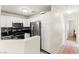 Charming kitchen with stainless steel appliances and dark countertops, adjacent to hallway leading to other rooms at 68 Belle Soleil Ave, Las Vegas, NV 89123