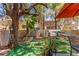 A cozy patio with seating and greenery, shaded by mature trees and a colorful umbrella at 68 Belle Soleil Ave, Las Vegas, NV 89123