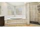 Bathroom showcasing a soaking tub, walk-in shower, and stylish marble-look tiling at 691 Vineland Ave, Henderson, NV 89052