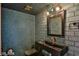 Stylish powder room featuring blue tile walls, black sink, and industrial-style lighting at 722 Barrie Ct, Henderson, NV 89002