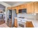 Modern kitchen with stainless steel refrigerator, gas range, and wood cabinets overlooking the living room at 801 Dana Hills Ct # 101, Las Vegas, NV 89134