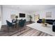 This living room with a dining area has dark hardwood floors, a large screen TV, and a sliding glass door to the backyard at 817 Cottonwood Hill Pl, Henderson, NV 89011