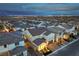 Aerial view capturing a twilight scene showcasing a well-lit home in a neighborhood with city lights in the distance at 8984 Rolling Pietra St, Las Vegas, NV 89166