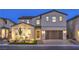 Two-story home boasting stucco exterior, a two-car garage, and a manicured front yard illuminated by landscape lighting at 8984 Rolling Pietra St, Las Vegas, NV 89166
