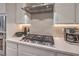 Close-up of a modern gas cooktop on marble countertops with stainless steel Kitchenaid hood vent at 8984 Rolling Pietra St, Las Vegas, NV 89166