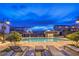 Community pool area with lounge chairs, lush landscaping, and ambient lighting for relaxation and recreation at 8984 Rolling Pietra St, Las Vegas, NV 89166