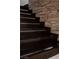 Dark wood staircase with built-in lighting and a stone accent wall at 9325 Canyon Classic Dr, Las Vegas, NV 89144