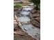 Water feature stream flows through stone landscape to backyard pool at 9325 Canyon Classic Dr, Las Vegas, NV 89144