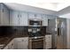 Close-up of a kitchen featuring stainless steel appliances, grey cabinets, and backsplash at 9449 Amber Valley Ln, Las Vegas, NV 89134