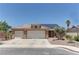 Exterior view of a desert home featuring a three car garage, solar panels and desert landscaping at 950 Marbelwood Ave, Las Vegas, NV 89123