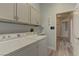 Well-lit laundry area with front load washer and dryer, upper cabinets and access to hallway at 950 Marbelwood Ave, Las Vegas, NV 89123