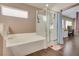 Bathroom featuring a soaking tub, glass enclosed shower, and wood floors at 9746 Vista Cache Ct, Las Vegas, NV 89148