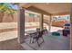 A covered outdoor patio with stone pillars, seating, and minimal desert landscaping at 9746 Vista Cache Ct, Las Vegas, NV 89148