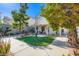 Well-maintained backyard featuring green grass, a paved seating area, and mature shade trees at 10413 Rising Harbor Ave, Las Vegas, NV 89129
