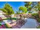 Outdoor dining area in a landscaped backyard with stone patio and seating for four at 10413 Rising Harbor Ave, Las Vegas, NV 89129