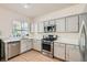 Well-lit kitchen with white cabinets, stainless steel appliances, tile floor and white countertops at 10413 Rising Harbor Ave, Las Vegas, NV 89129