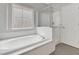 Modern bathroom featuring a separate shower, a large soaking tub, and a frosted glass window at 121 Staplehurst Ave, Henderson, NV 89002