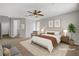 Staged main bedroom showcasing neutral tones, plush carpet, a ceiling fan, and bright natural light at 121 Staplehurst Ave, Henderson, NV 89002