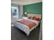 Bright bedroom featuring a bed with colorful bedding, a green accent wall, and natural light from the window at 1900 Arietta Vista St, Henderson, NV 89044