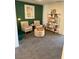 Comfortable sitting area featuring neutral-toned chairs, a woven ottoman, and stylish shelving against a green accent wall at 1900 Arietta Vista St, Henderson, NV 89044