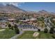 Expansive aerial view of a golf community clubhouse, surrounded by lush landscaping, mountains and residential homes at 2624 Spalding Dr, Las Vegas, NV 89134