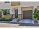 Three story townhouse with a gray door, one car garage and xeriscaped lawn at 2747 Tahiti Grape Way # 2, Las Vegas, NV 89183