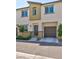 Three story townhouse with a gray door, one car garage and xeriscaped lawn at 2747 Tahiti Grape Way # 2, Las Vegas, NV 89183