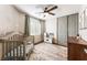 A cozy bedroom featuring a crib, ceiling fan, patterned rug, and gray closet at 4508 Dragon Fly Creek Ave, North Las Vegas, NV 89031