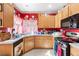 Functional kitchen with wood cabinets, stainless steel appliances, and red accent wall at 5539 Foxtail Ridge St, North Las Vegas, NV 89031