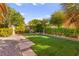 Well-manicured backyard with lush green lawn, mature trees, and privacy hedging at 5680 N Fort Apache Rd, Las Vegas, NV 89149