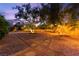 Night shot of a backyard with desert landscaping, gravel, stone pavers, and mature trees at 5680 N Fort Apache Rd, Las Vegas, NV 89149