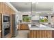 Modern kitchen with stainless steel appliances, granite countertops, and custom wood cabinetry at 5680 N Fort Apache Rd, Las Vegas, NV 89149