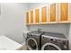 Well-lit laundry room equipped with modern washer and dryer and ample cabinet space at 5680 N Fort Apache Rd, Las Vegas, NV 89149