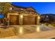 Three-car garage with stone accents, brown doors, and wide driveway surrounded by landscaped front yard at 7311 Spring Flower Ave, Las Vegas, NV 89117