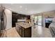 Open-concept kitchen featuring stainless appliances, granite island, dark cabinets, and a view of dining area and backyard at 7311 Spring Flower Ave, Las Vegas, NV 89117