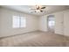 A carpeted bedroom with ceiling fan and a view to a hallway at 7525 Royal Crystal St, Las Vegas, NV 89149