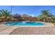 Backyard pool with rock feature, concrete surround, and desert landscaping at 7525 Royal Crystal St, Las Vegas, NV 89149