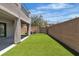 Beautiful backyard featuring artificial grass, a brick wall, and an exterior covered patio area at 7775 Santos Bay Ct, Las Vegas, NV 89179