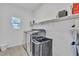 Well-lit laundry room with a washer, dryer, and overhead shelving for storage of supplies at 7775 Santos Bay Ct, Las Vegas, NV 89179