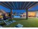 Serene backyard featuring a pool, outdoor kitchen, pergola-covered patio, and well-manicured lawn at 8713 Long Winter Ct, Las Vegas, NV 89131