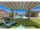 Inviting backyard oasis with a refreshing pool, covered lounge area, and lush artificial grass at 8713 Long Winter Ct, Las Vegas, NV 89131