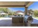 Great outdoor kitchen and bar with stainless steel grill overlooking the pool and landscaped backyard at 8713 Long Winter Ct, Las Vegas, NV 89131
