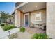 Covered front porch with brick flooring, seating, manicured landscaping, and a blue front door at 912 Allister Fields Ln, Las Vegas, NV 89138