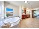 Bright bathroom featuring a luxurious soaking tub, a double sink vanity, and an arched doorway at 9628 Matanzas Creek Ct, Las Vegas, NV 89139