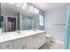 Well-lit bathroom with a double sink vanity, large mirror, and a shower with a curtain at 9883 Russian Hill St, Las Vegas, NV 89141