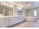 Well-lit bathroom with double sinks, large mirror, soaking tub, and natural light at 9883 Russian Hill St, Las Vegas, NV 89141