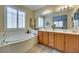 Bright bathroom showcasing a large soaking tub, double vanity, and wood-look tile at 1000 Via Canale Dr, Henderson, NV 89011