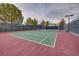 A fenced tennis court with well-maintained surface and surrounding greenery at 1000 Via Canale Dr, Henderson, NV 89011
