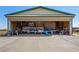 View of Airplane Hangar, concrete floor, with bi-fold door open, airplane inside, and storage shelves at 1100 Mitchell Pl, Pahrump, NV 89060